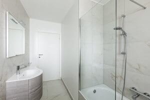 bathtub shower doors in a white marble bathroom
