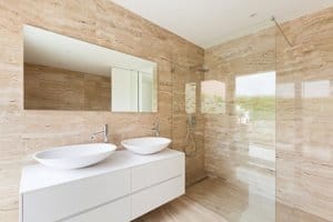 light tan stone bathroom with glass shower enclosure